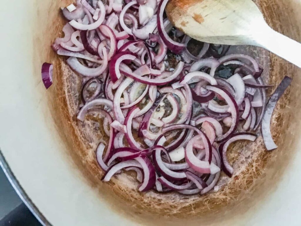 Red onions sauteeing in a pan.