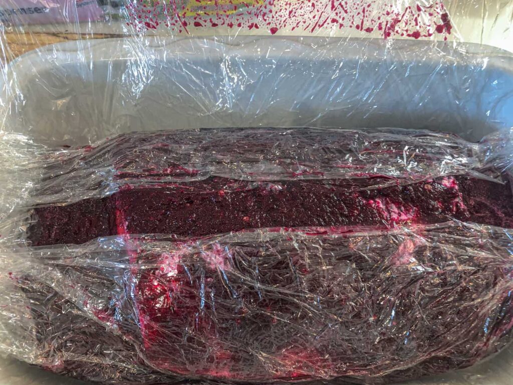 Beetroot cure applied to a side of salmon and wrapped in cling film to keep it contained.