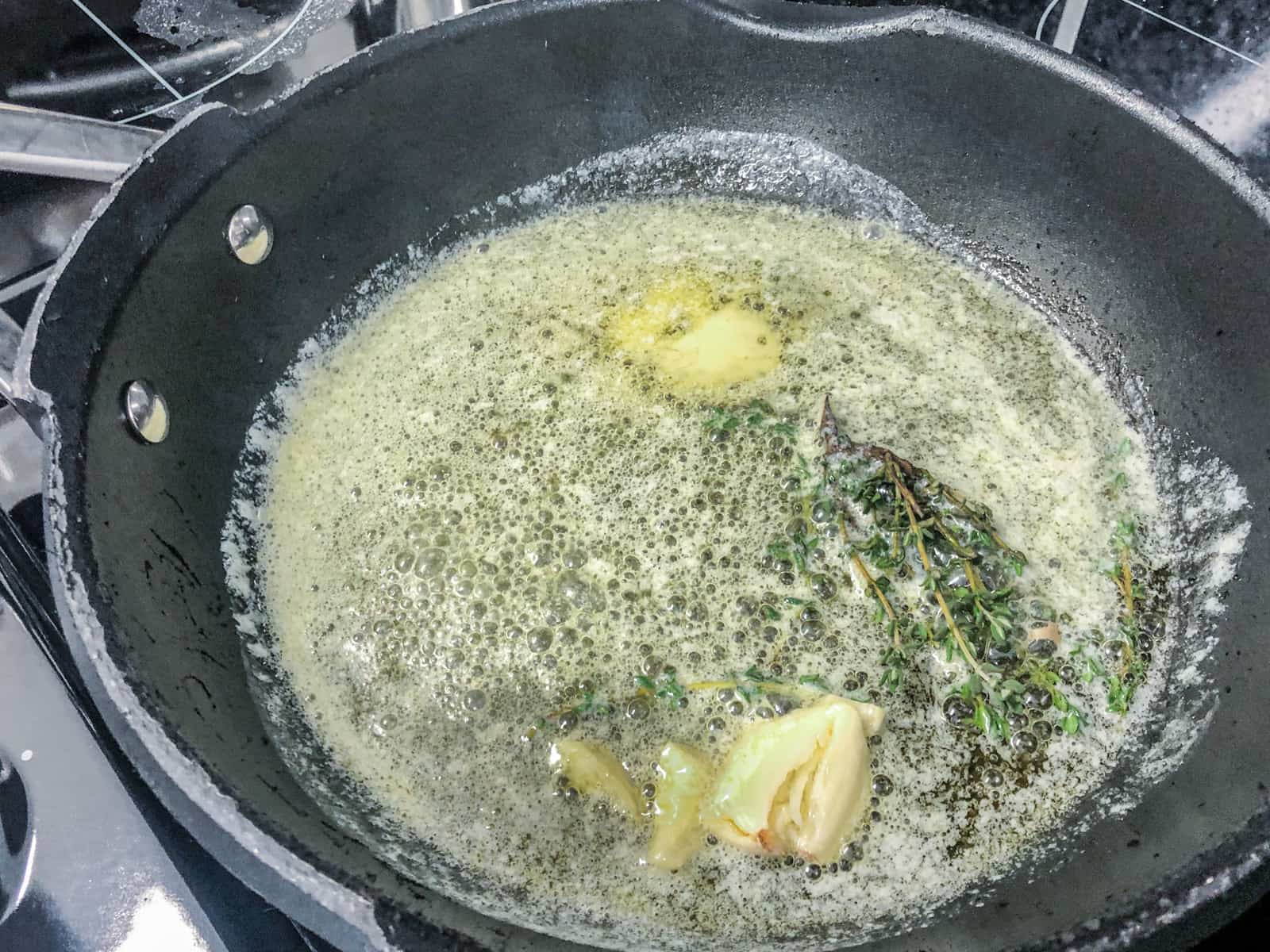 Butter melted and just starting to froth with garlic and fresh thyme leaves in a heavy based frypan.
