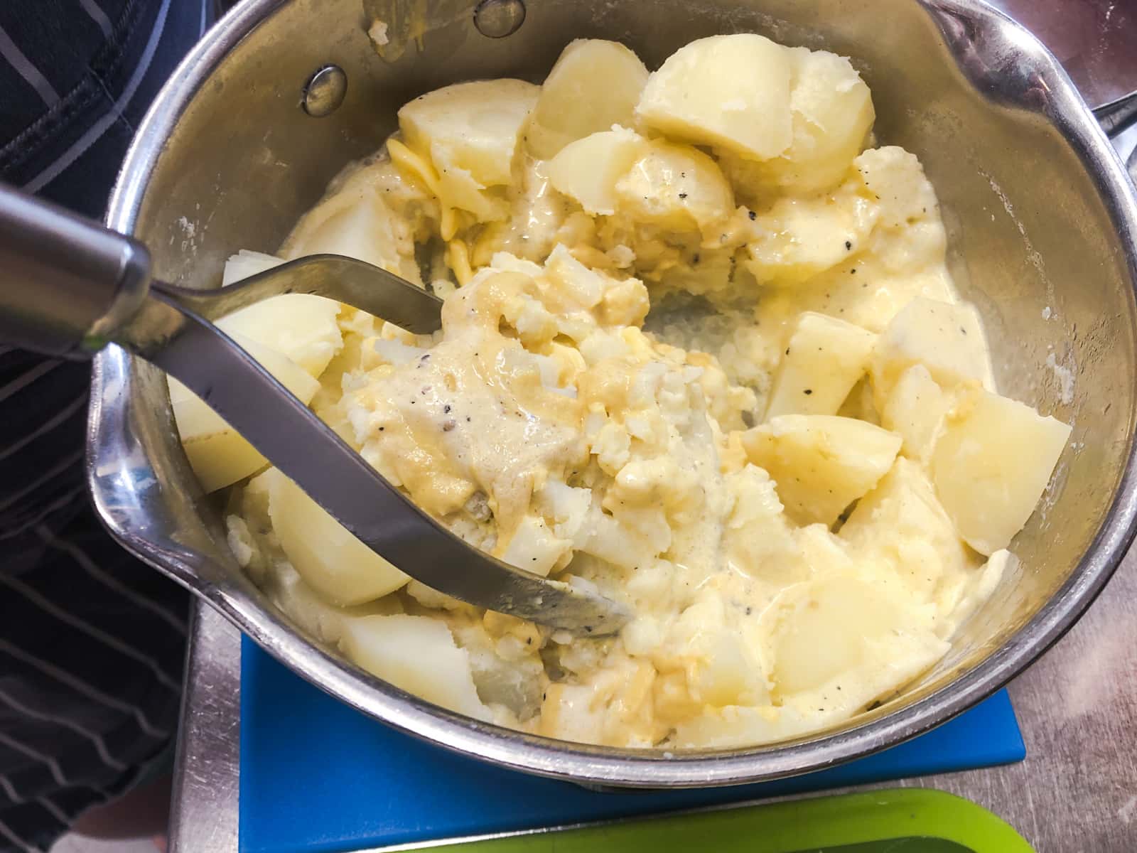 Mashing potatoes in a large pan.