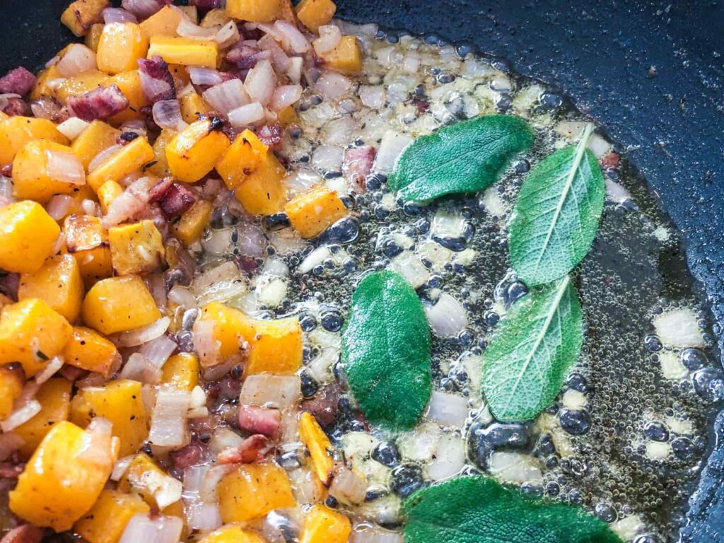 Squash, shallots and bacon cooking and fresh sage leaves added to fry until crispy and flavour the oil.
