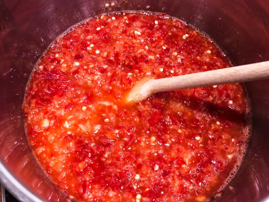 Chilli jam in a pot simmering and just starting to bubble.