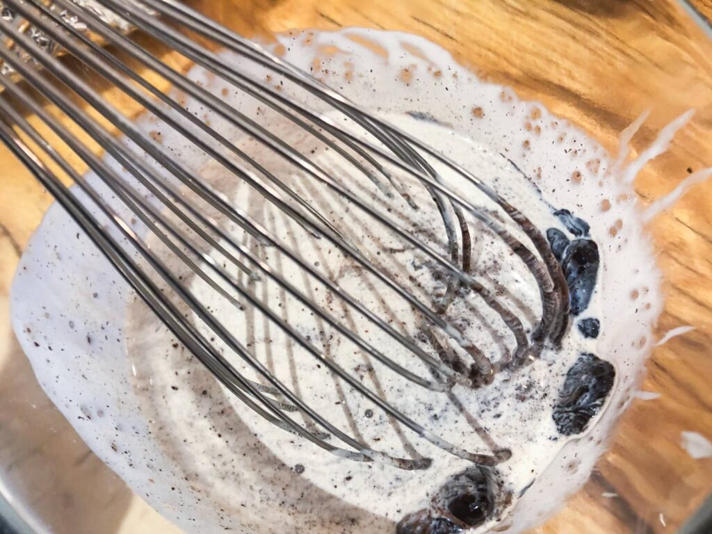 Whisking double cream and melted chocolate to incorporate all together.