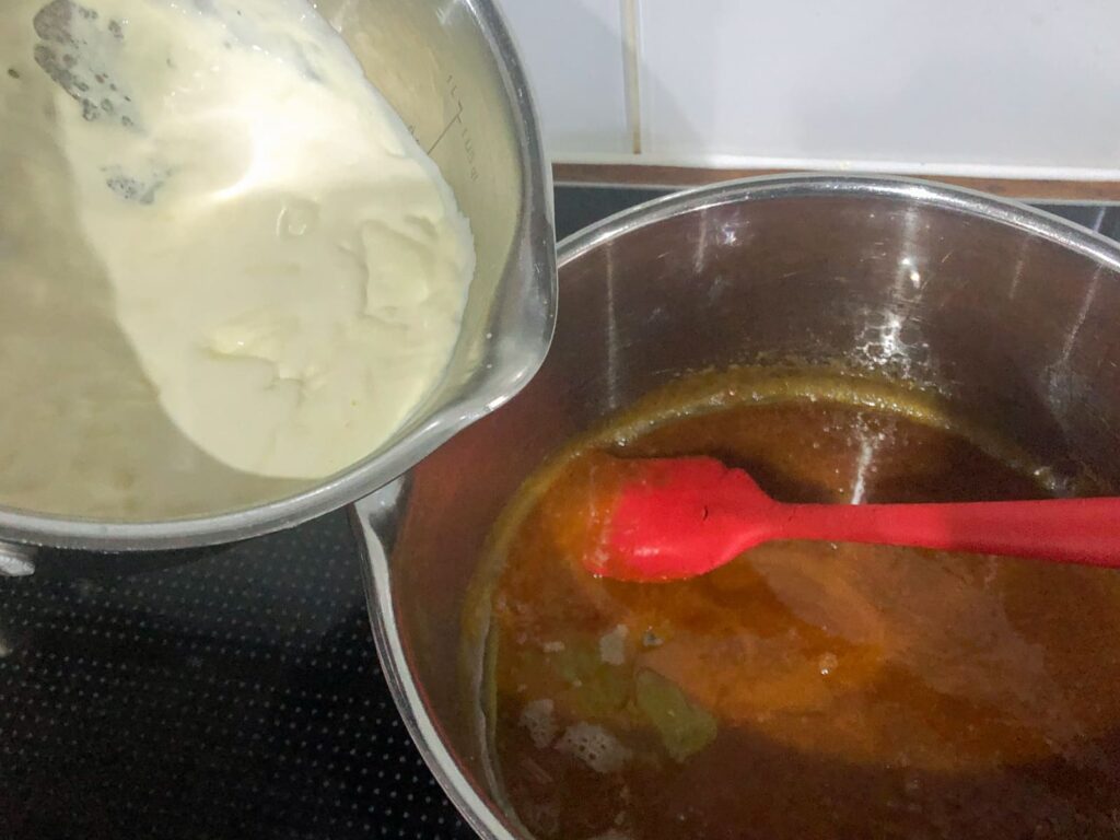 Adding cream that has been lightly whipped to a pan of caramel.