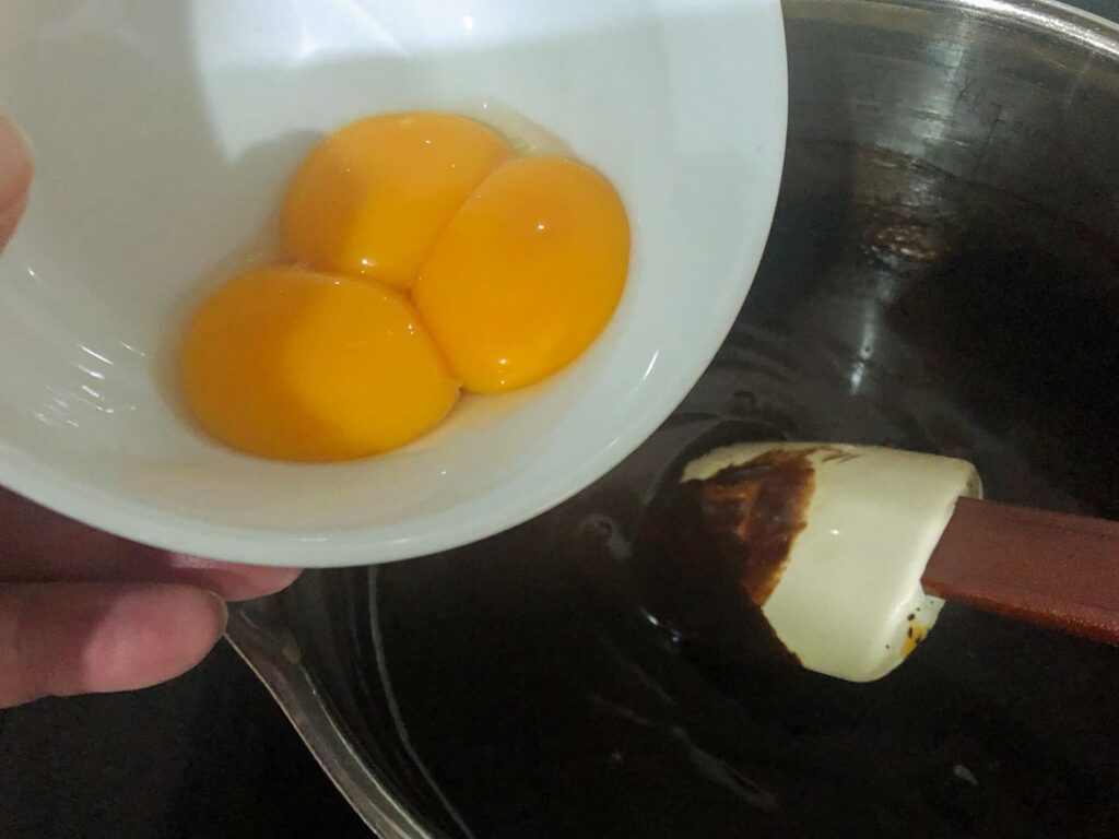 Egg yolks being added to melted chocolate.