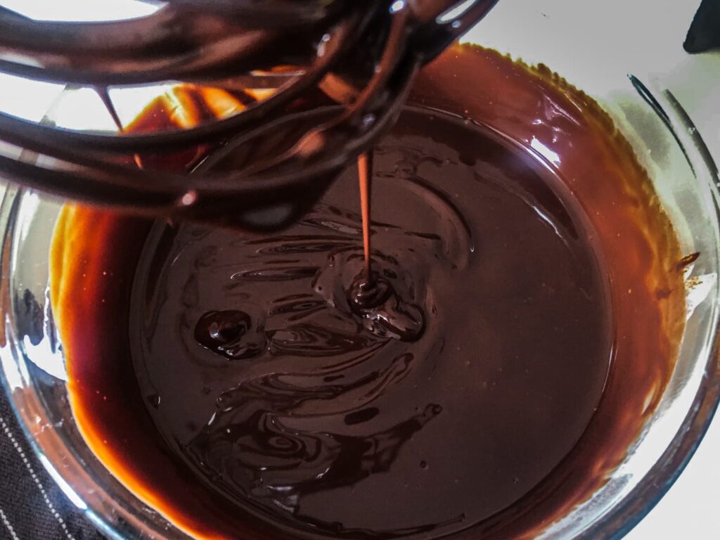 A rich dark chocolate ganache with a texture of ribbons ready to be chilled before whisking.