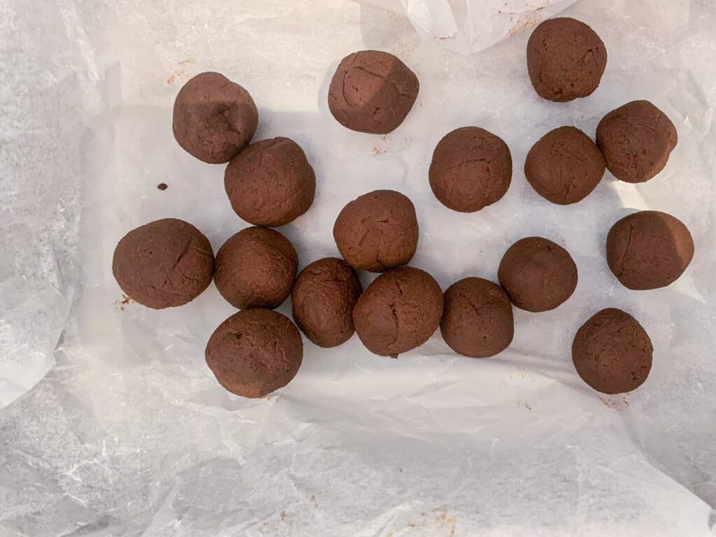 Small balls of chocolate ganache ready to be rolled in cocoa powder or crushed nuts to make truffles.