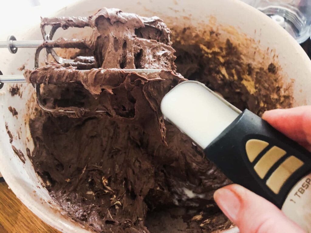 Adding milk to chocolate cake batter.