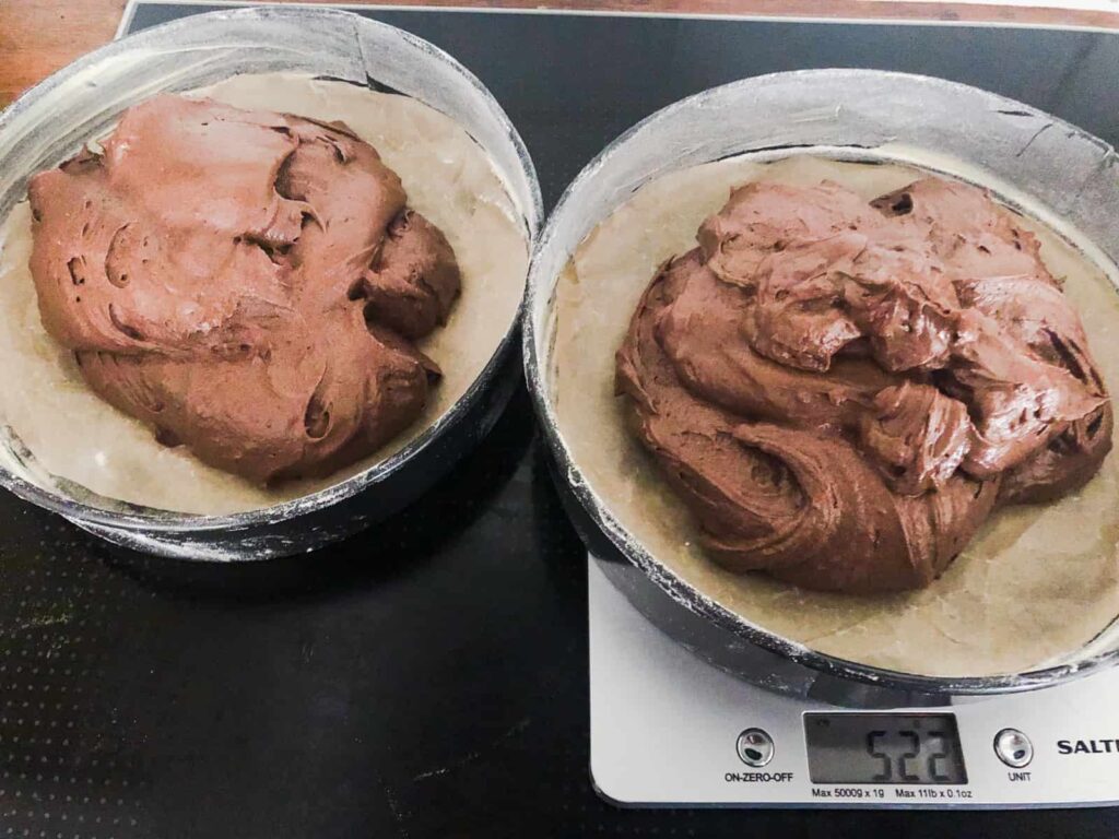 2 chocolate sponge cakes evenly split into tins before being baked.