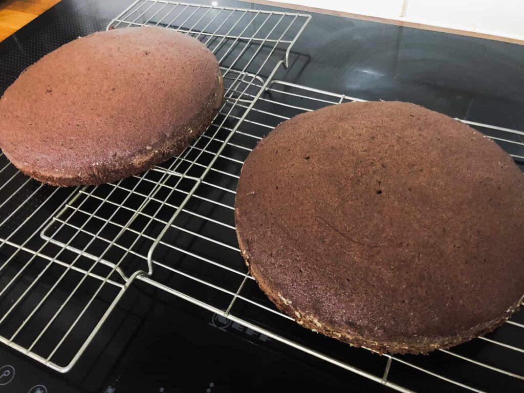 2 chocolate sponge cakes on cooling racks.