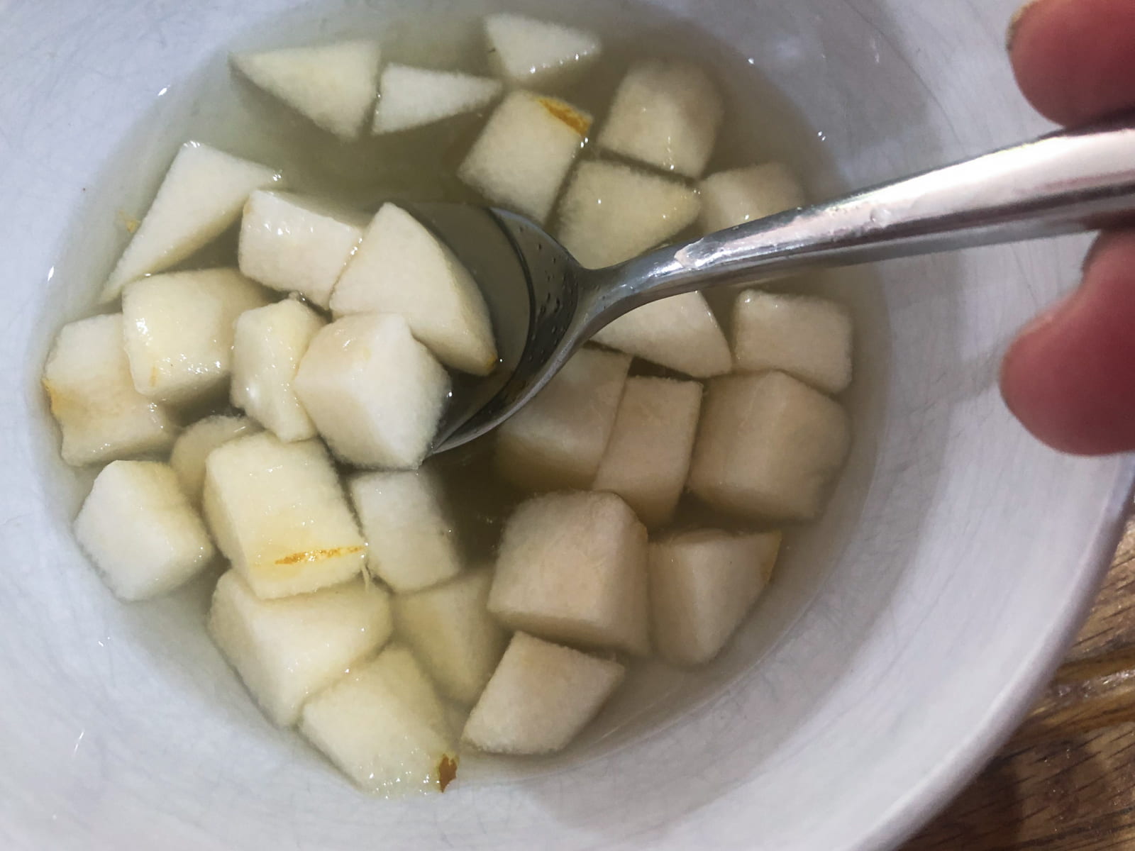 Cubed pieces of pear sitting in a small bowl of mild pickling liquor.