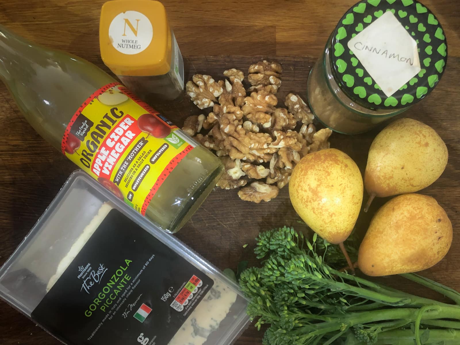 Ingredients for a pear and broccoli salad, including cider vinegar, blue cheese, walnuts, pears and broccoli and spices.