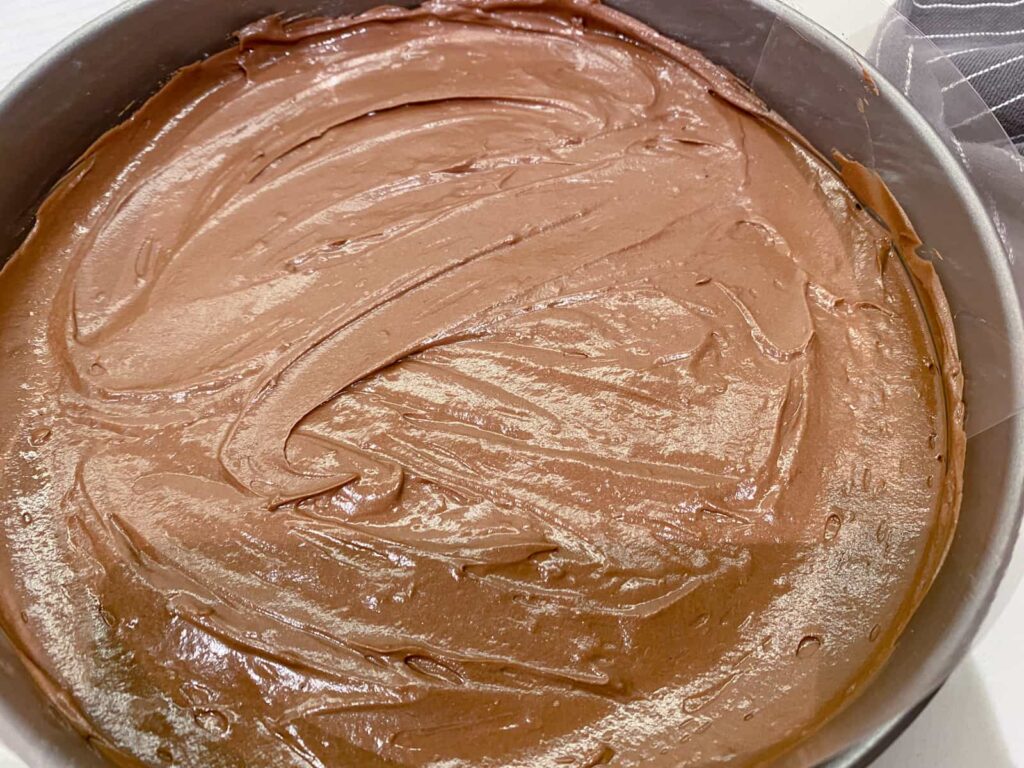 A no bake dark chocolate orange cheesecake filling spread into the tin ready to place in the fridge for chilling.