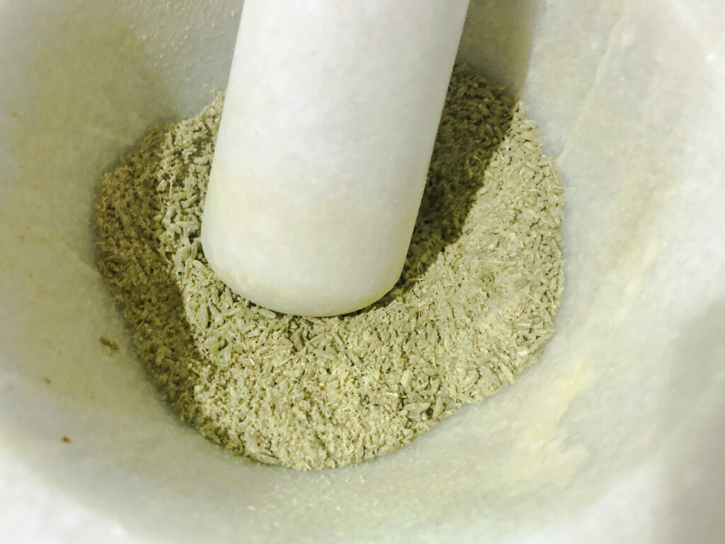 Grinding fennel seeds in a pestle and mortar.