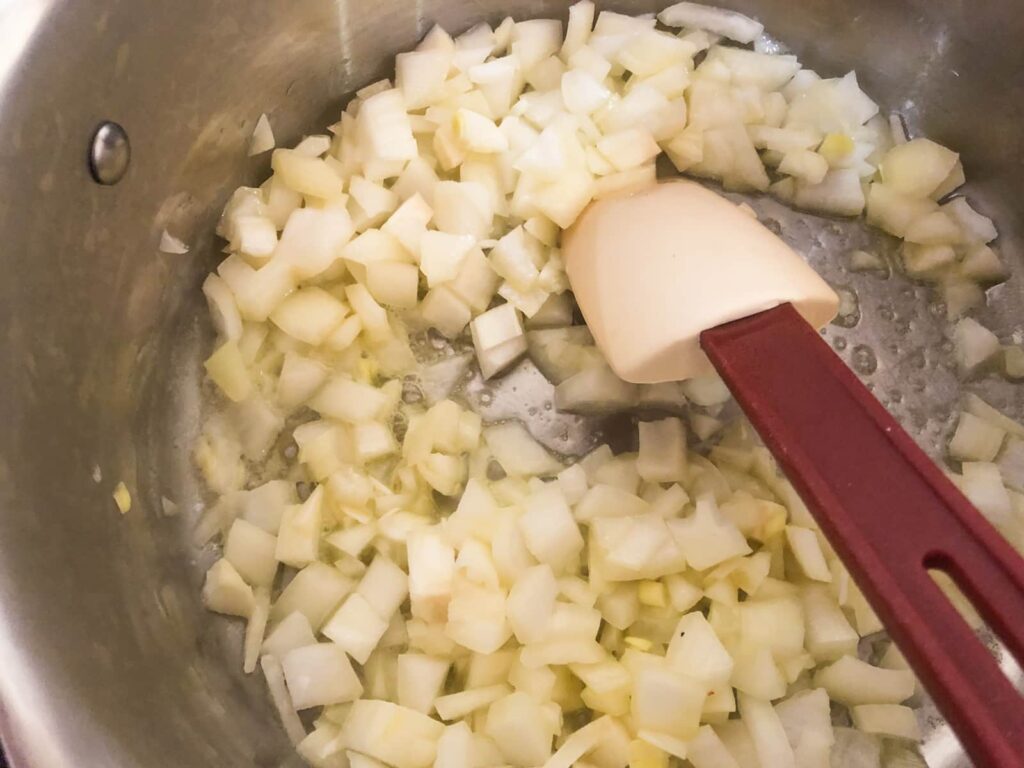 Chopped white onions slowly cooking in a pan with some oil and butter.