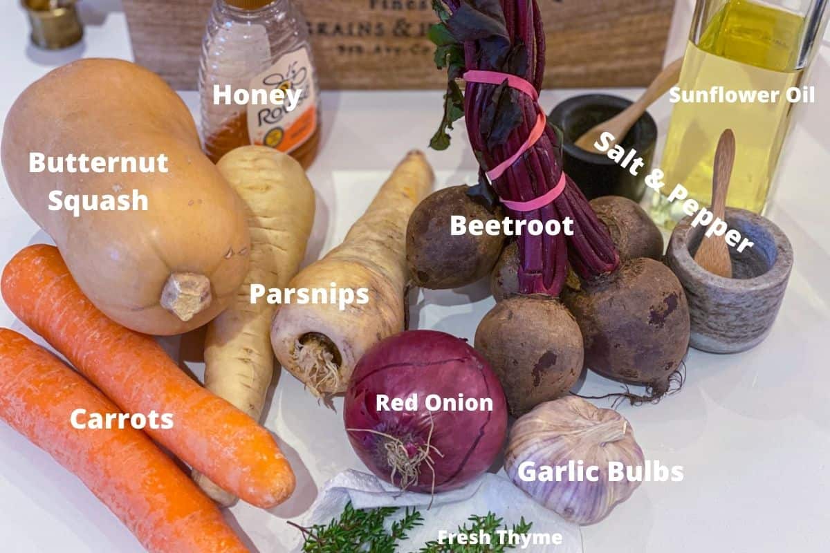 Ingredients to make sheet pan honey roasted vegetables including red onion, garlic, thyme, butternut squash, carrots, parsnips and beetroot.
