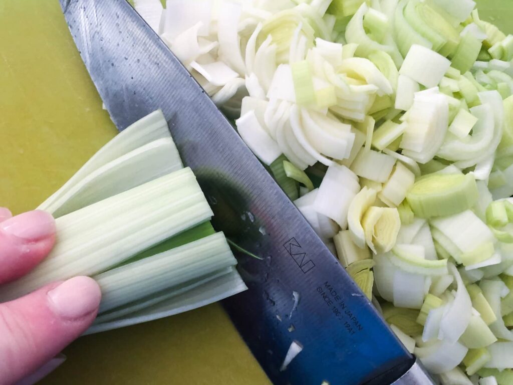 Freshly chopped leeks on a green chopping board.