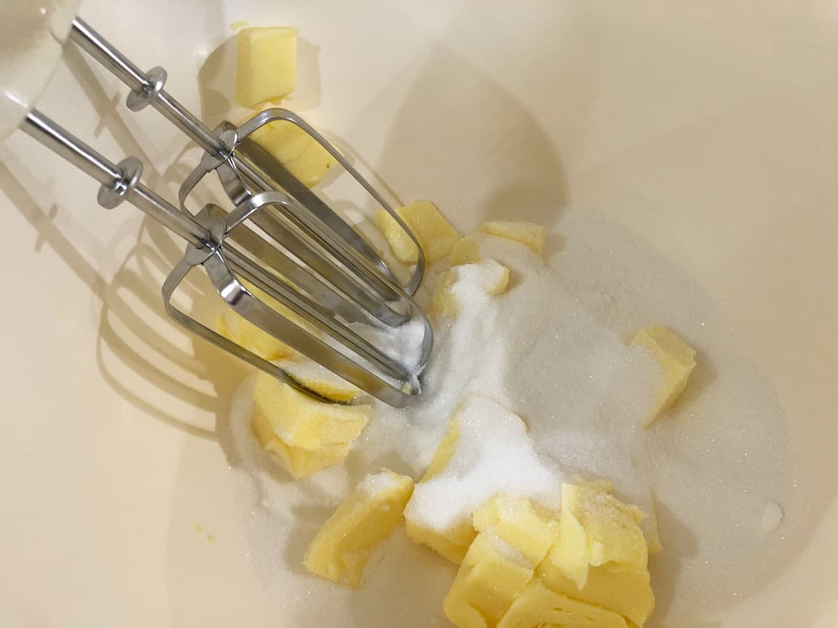 Mixing butter and sugar with a hand mixer.