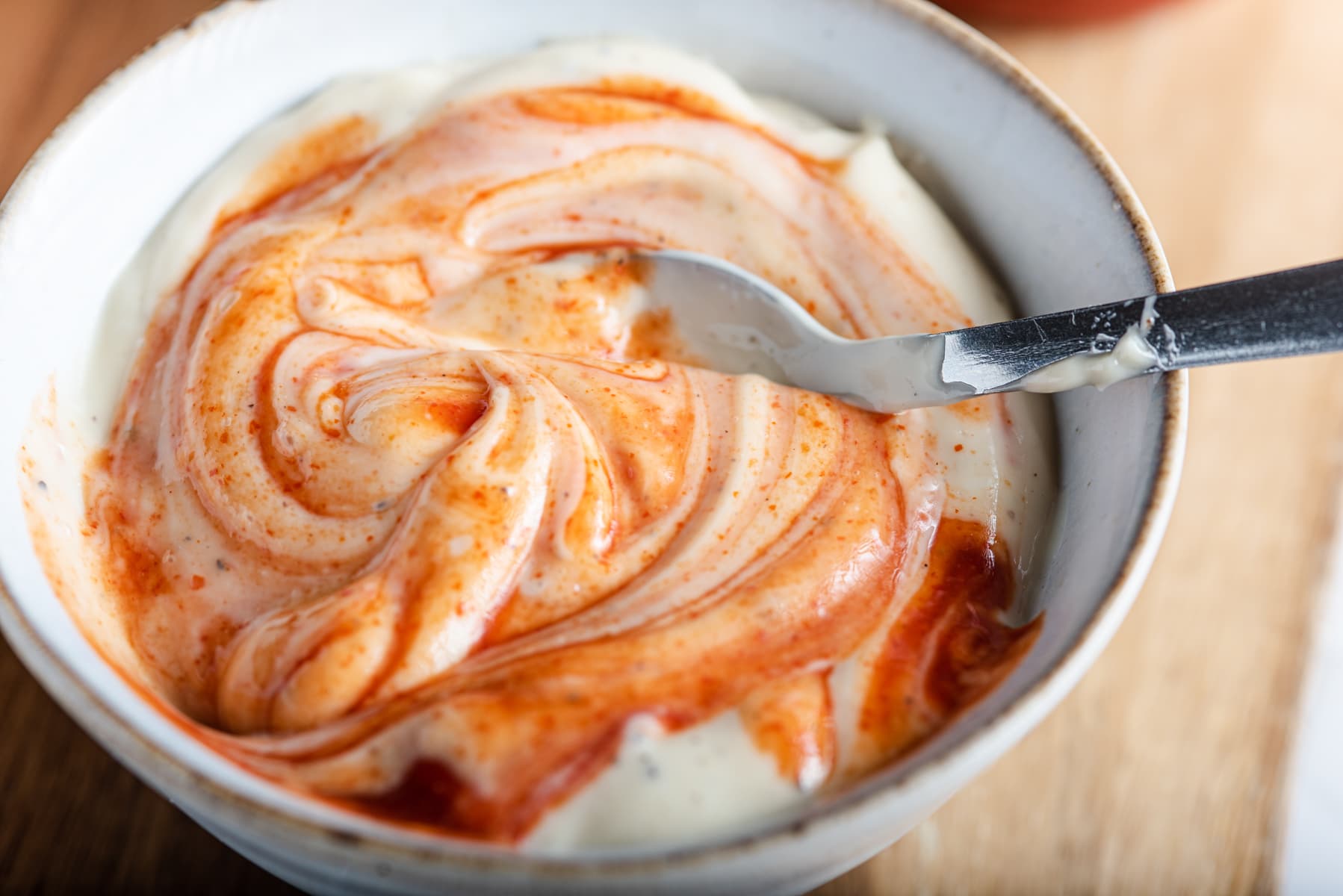 A bowl of homemade mayonnaise swirled with spicy sriracha sauce.
