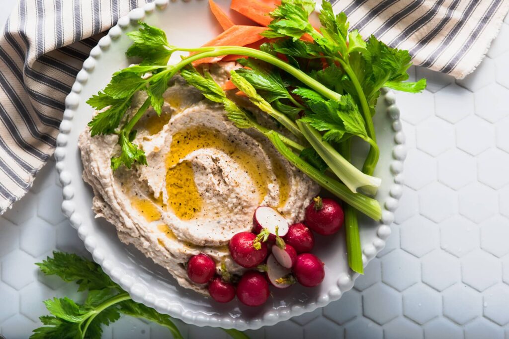 A gorgeous and fresh plate of vegetables with a white bean and garlic dip drizzled in olive oil.