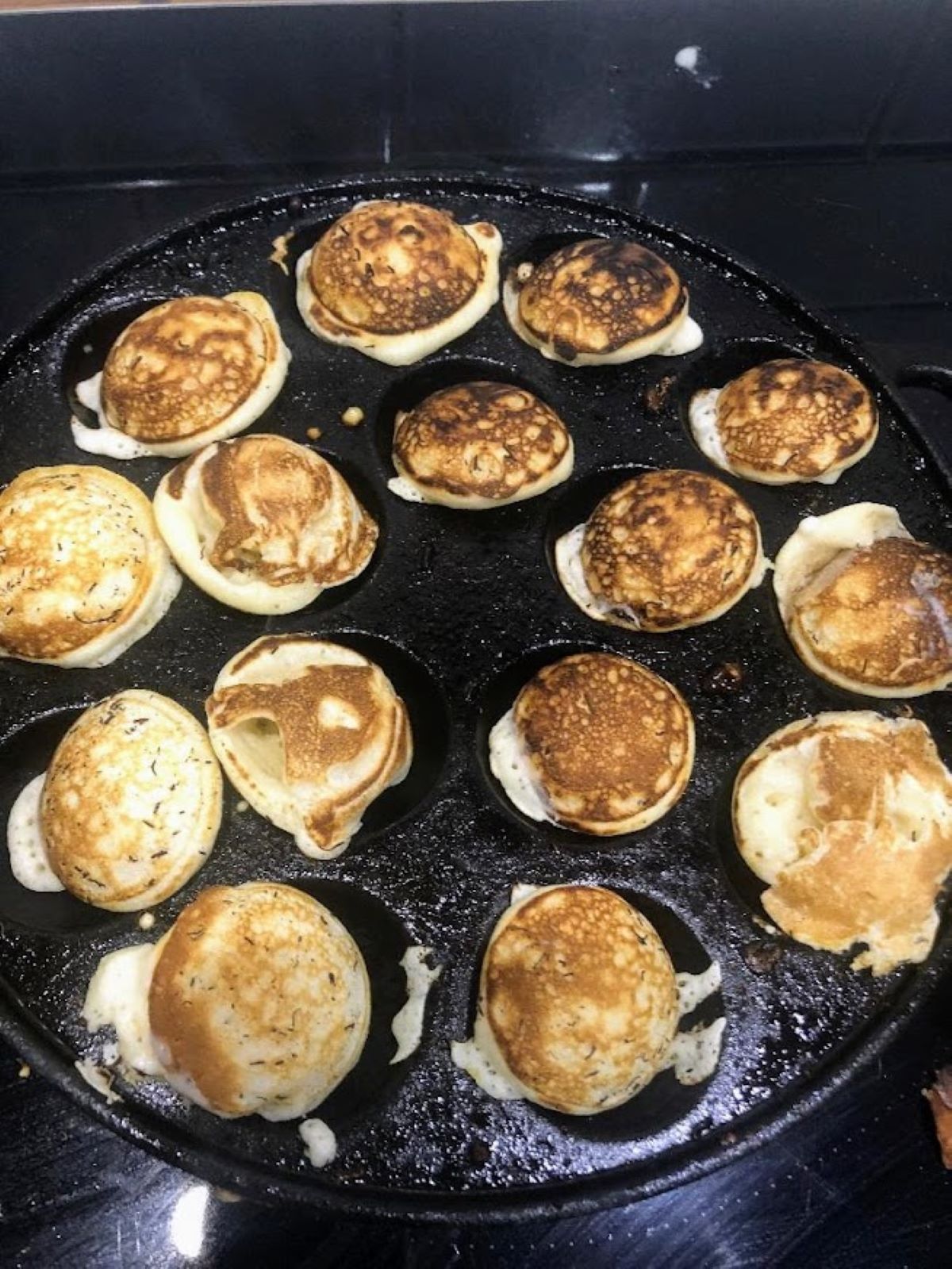 cast iron poffertjes pan filled with cooked pancakes