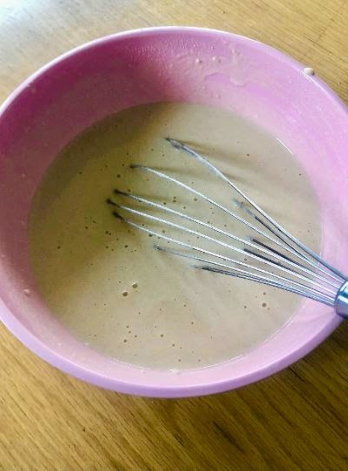 pink bowl filled with poffertjes batter and a whisk