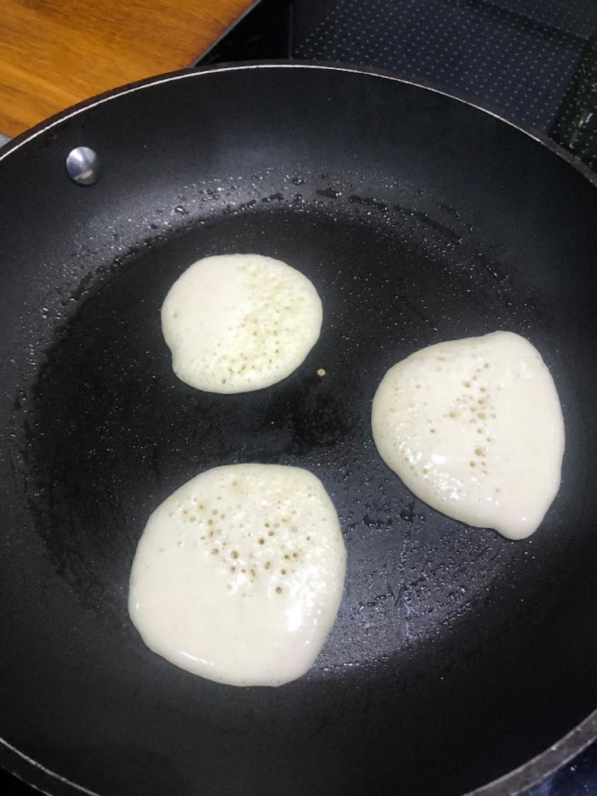 Dutch mini pancakes being cooked in a non stick pan ready for flipping over