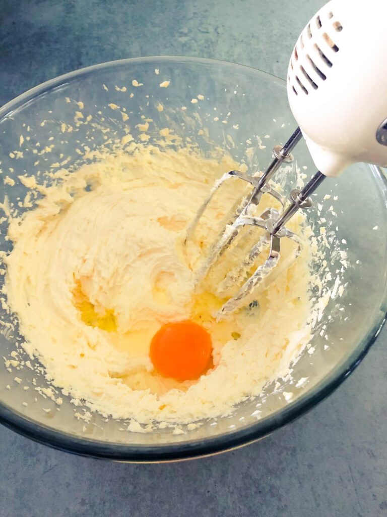 glass bowl with cake batter and eggs being whisked in