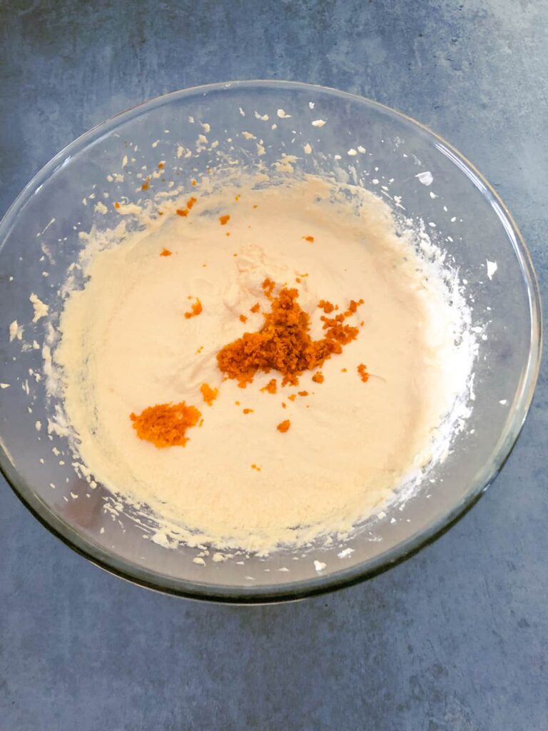 glass bowl of orange cake batter with added orange zest