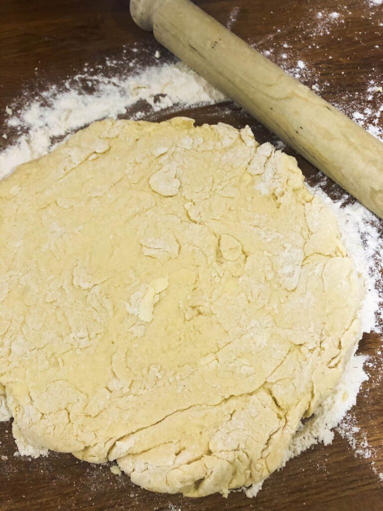 rolled out cheese scone dough on a floured wooden board with a rolling pin set alongside