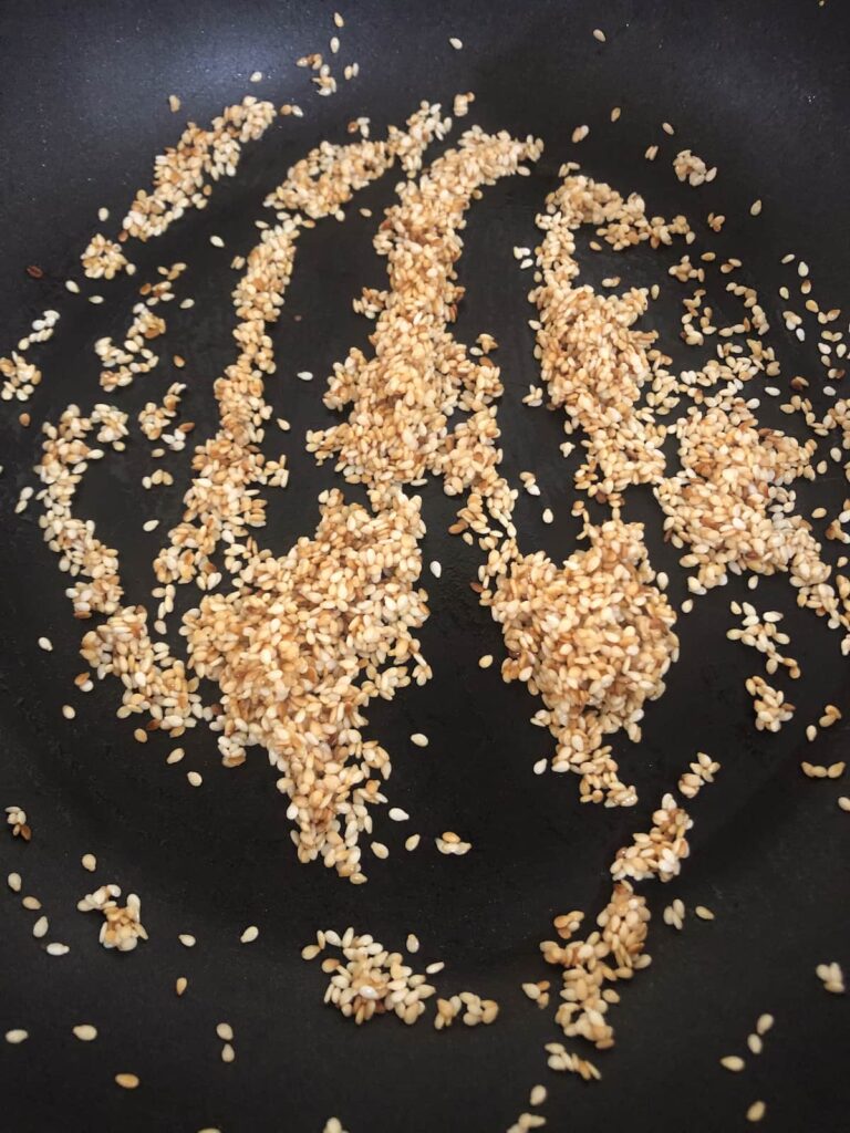 A non stick pan filled with toasted sesame seeds.