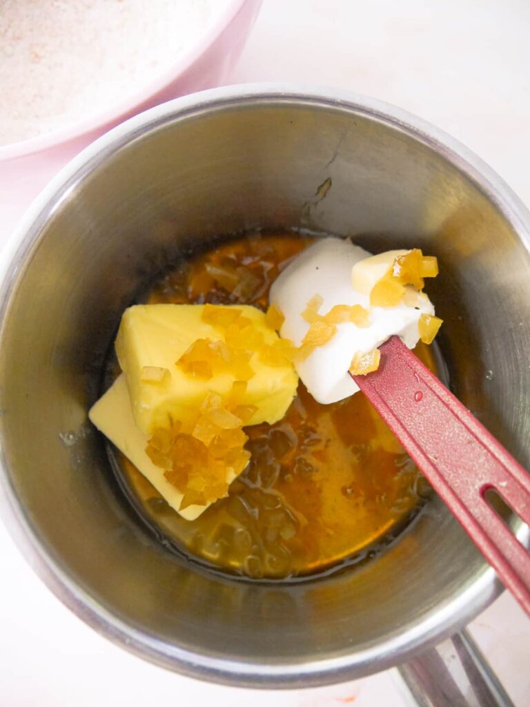 Saucepan filled with honey, syrup butter and cubes of stem ginger.