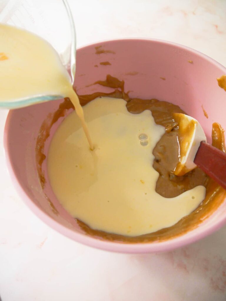 A jug of egg and milk being stirred into cake batter.