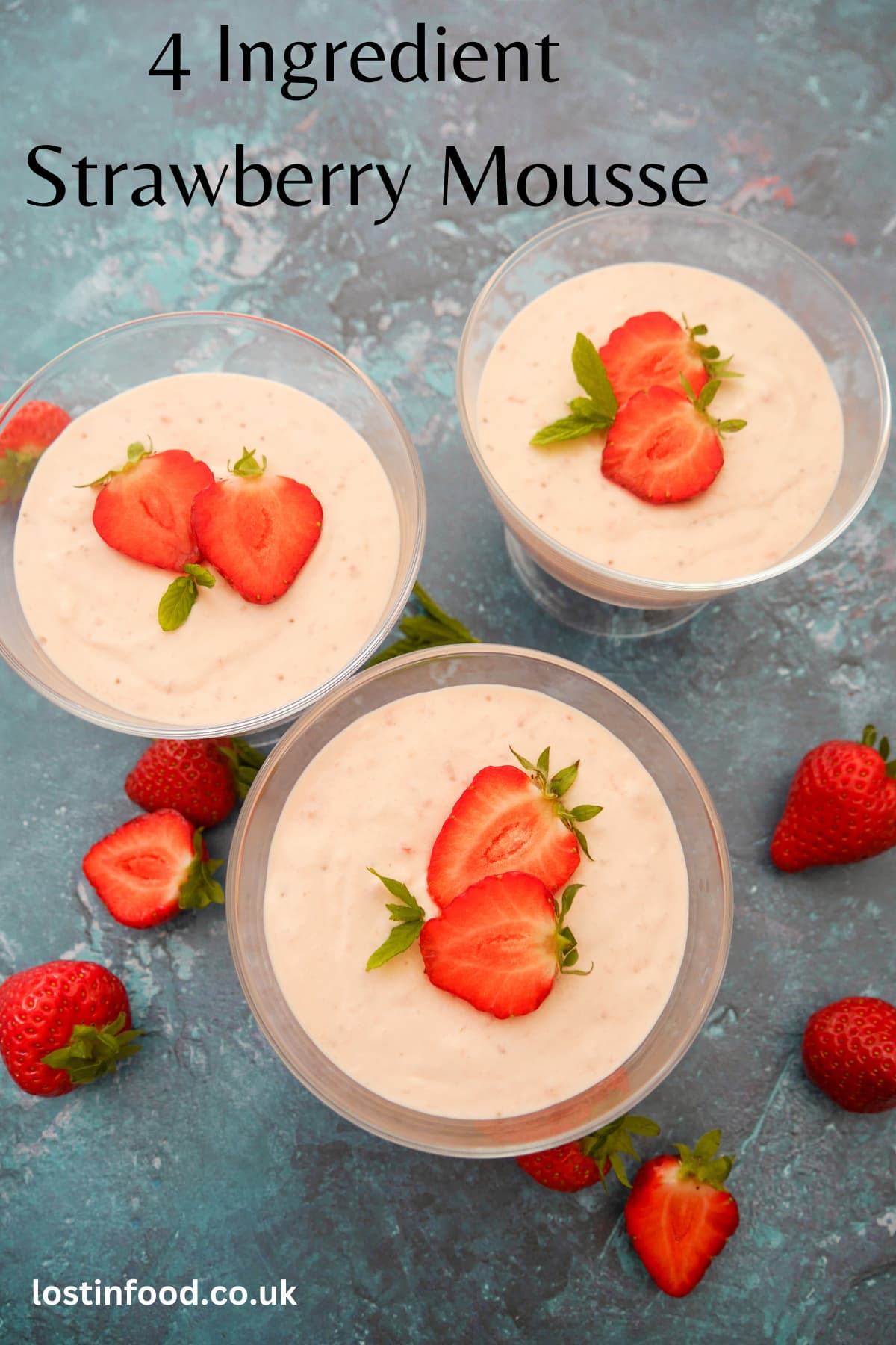 Pinnable image with recipe title and three individual glass serving dishes filled with strawberry mousse topped with sliced strawberries and mint leaves, with whole strawberries set alongside.