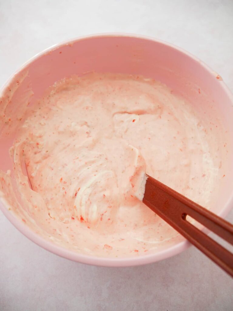 A pink bowl filled with strawberry mousse mixture.