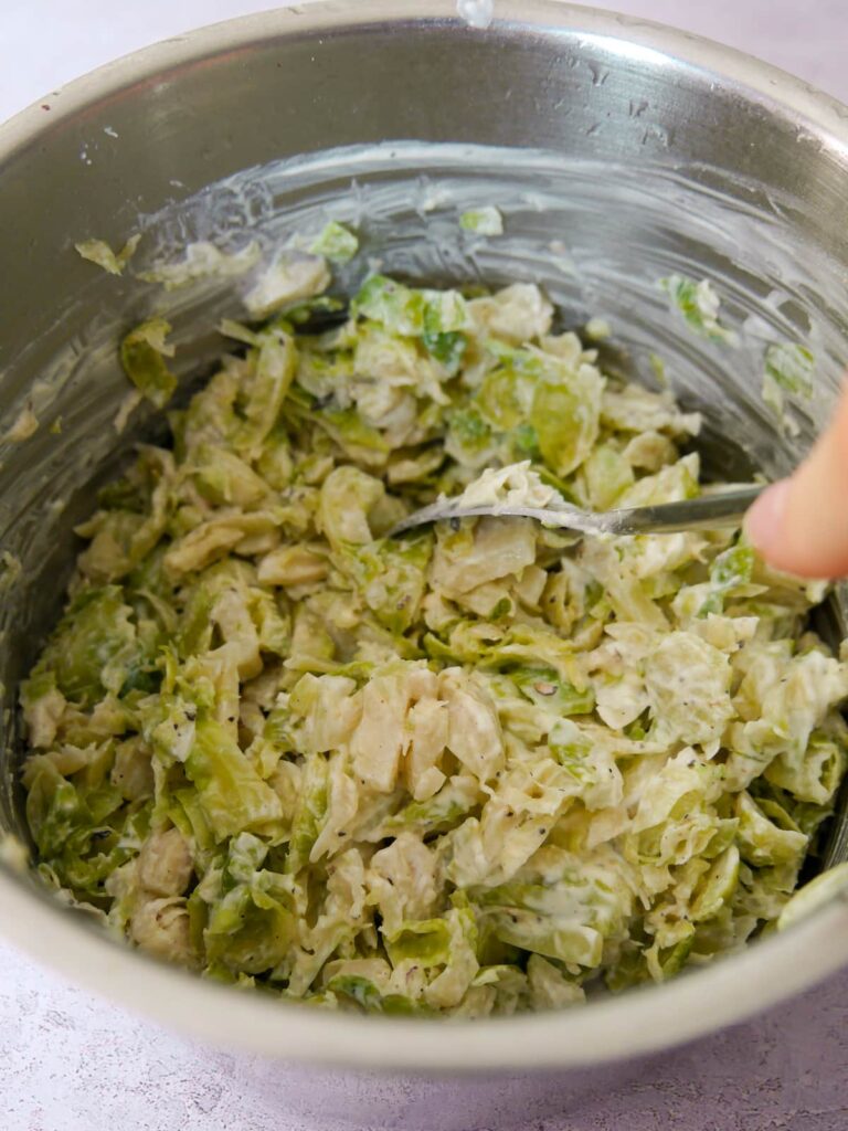 A saucepan filled with shredded Brussels sprouts coated in a cream sauce.