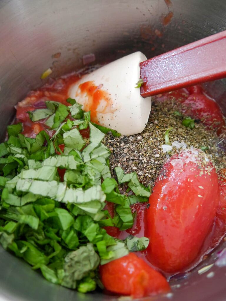 A saucepan of tomato and basil sauce ingredients.