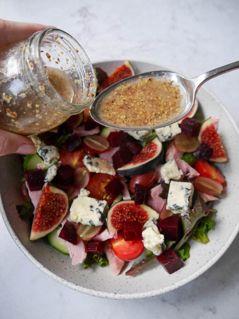 Red wine vinaigrette being spooned over a bowl of salad.