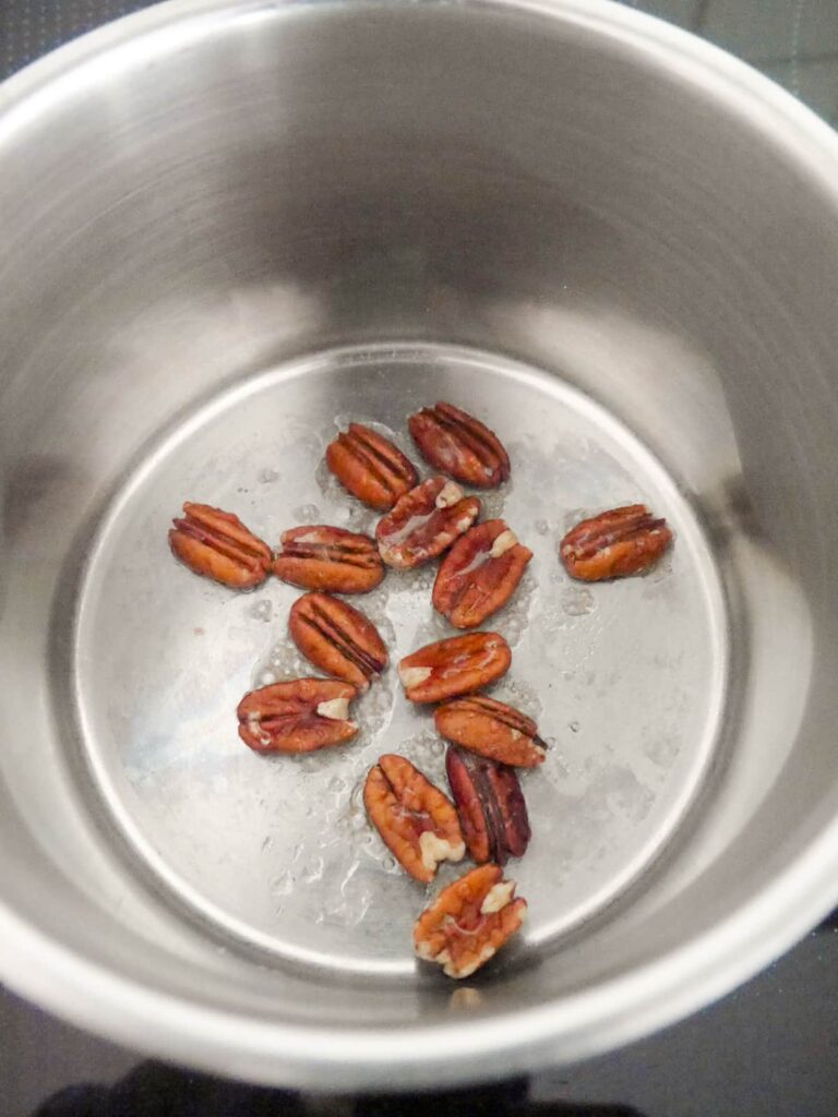 A saucepan with whole pecans and honey.