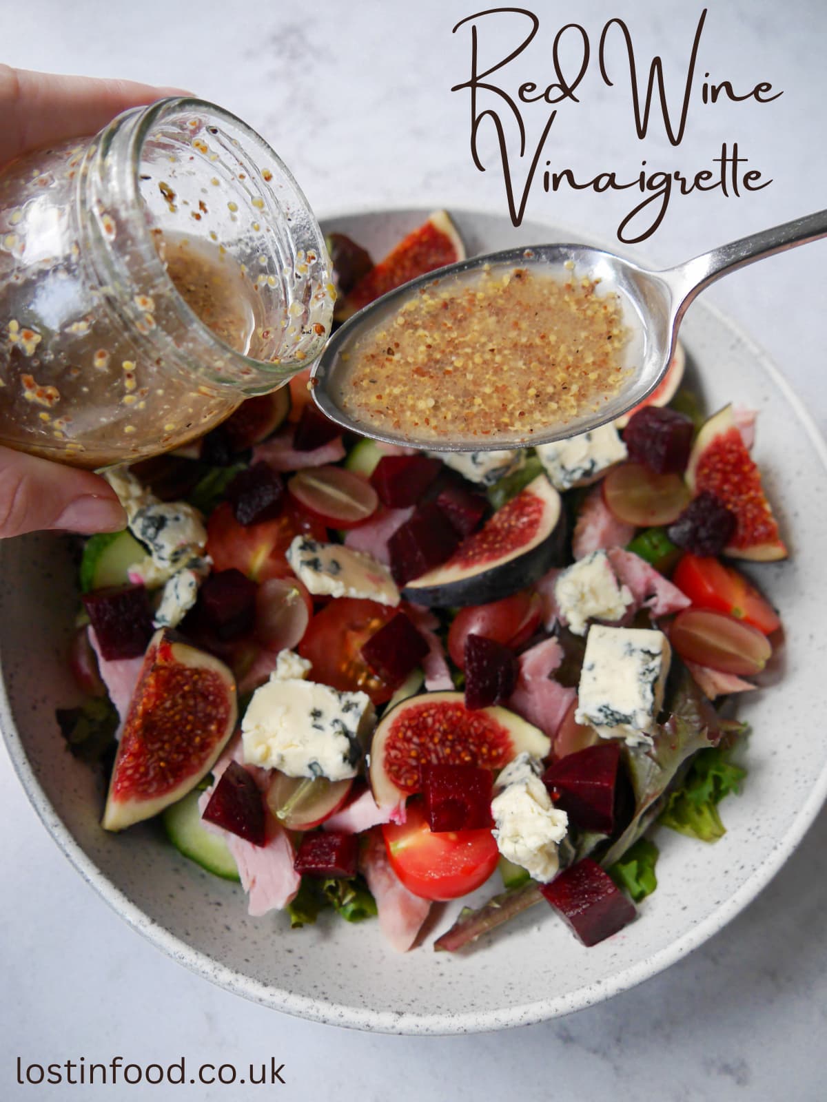 Pinnable image with recipe title and red wine vinaigrette being spooned over a ham, fig and blue cheese salad.