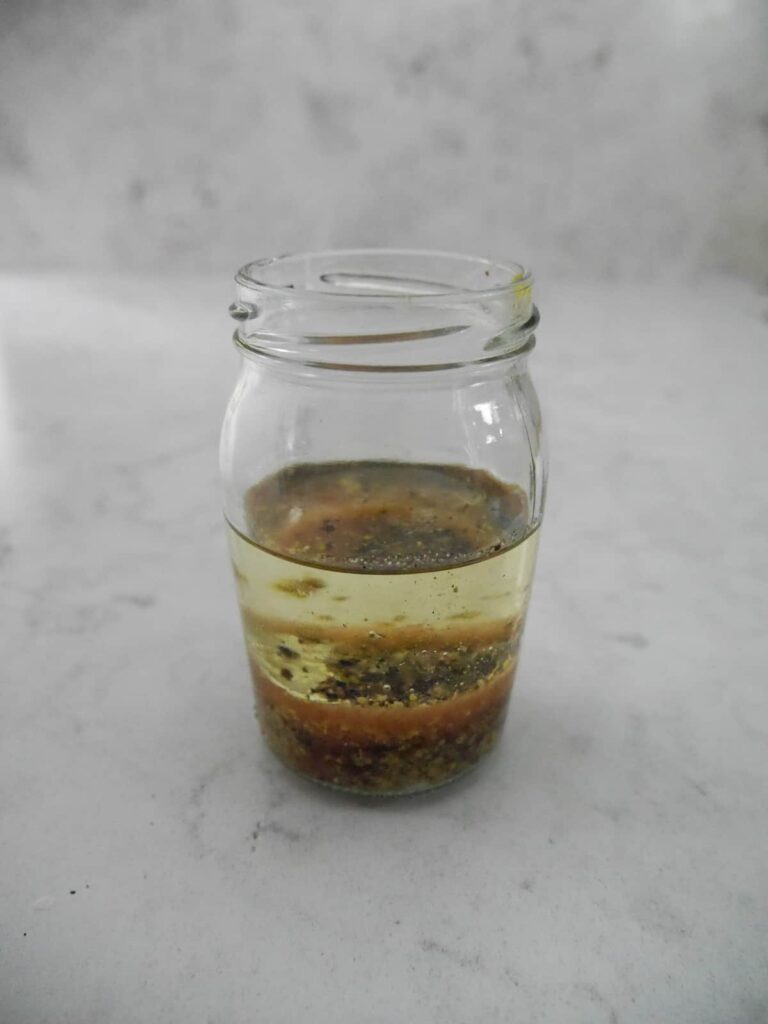 Red wine vinaigrette ingredients layered into a jar.