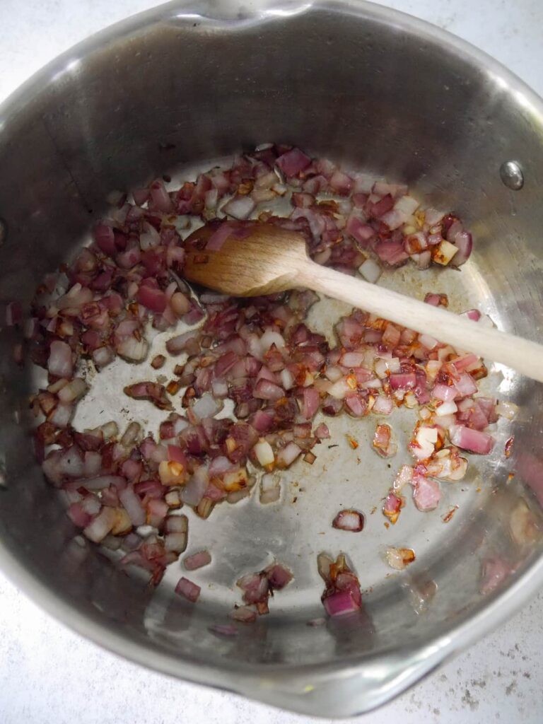A large saucepan filled with sauteed red onions.