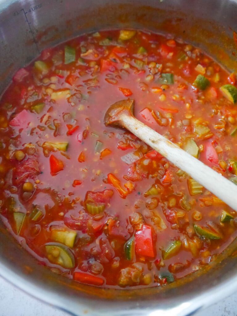 A large saucepan filled with cooked tomato and vegetable soup.