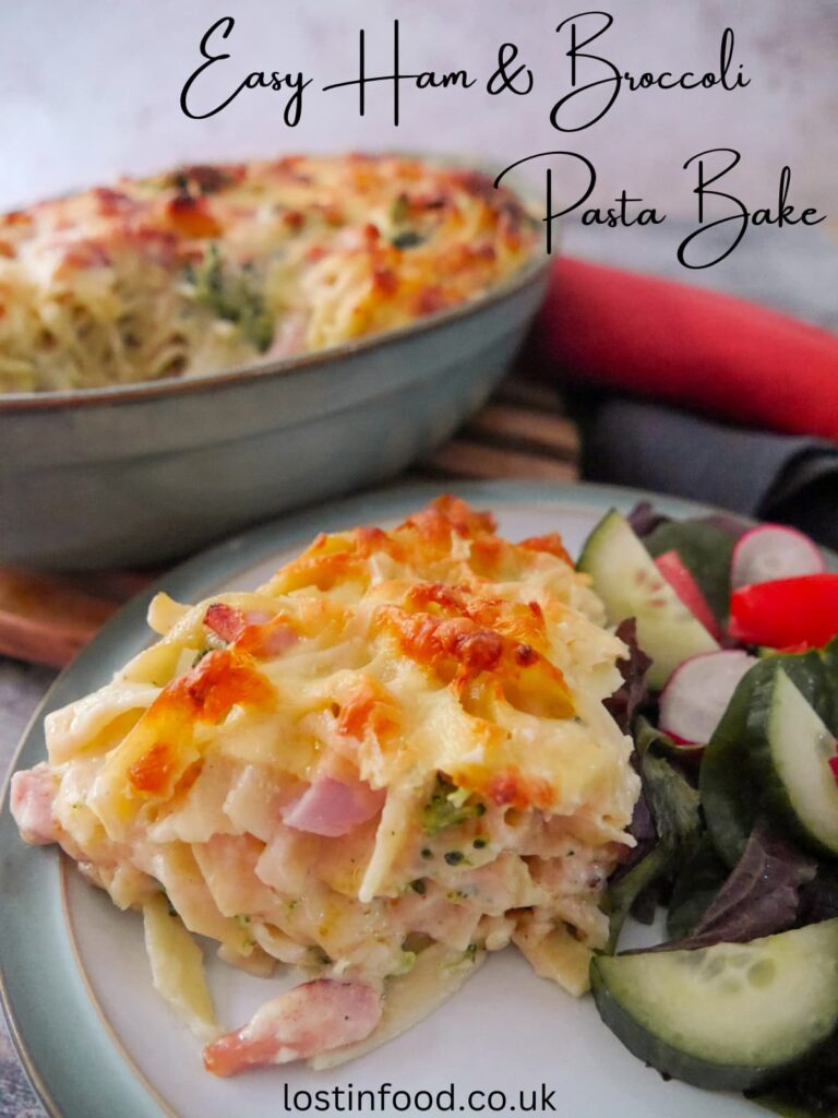 Pinnable image with recipe title and a plate with a serving of ham and broccoli pasta bake with salad, and a dish of pasta bake set alongside.