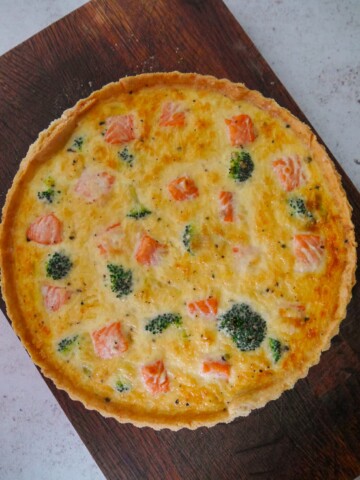 Salmon tart with broccoli set on a wooden platter.