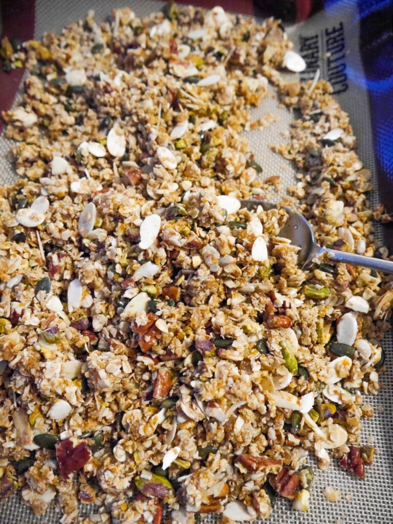 Part baked granola mix being stirred with a spoon.