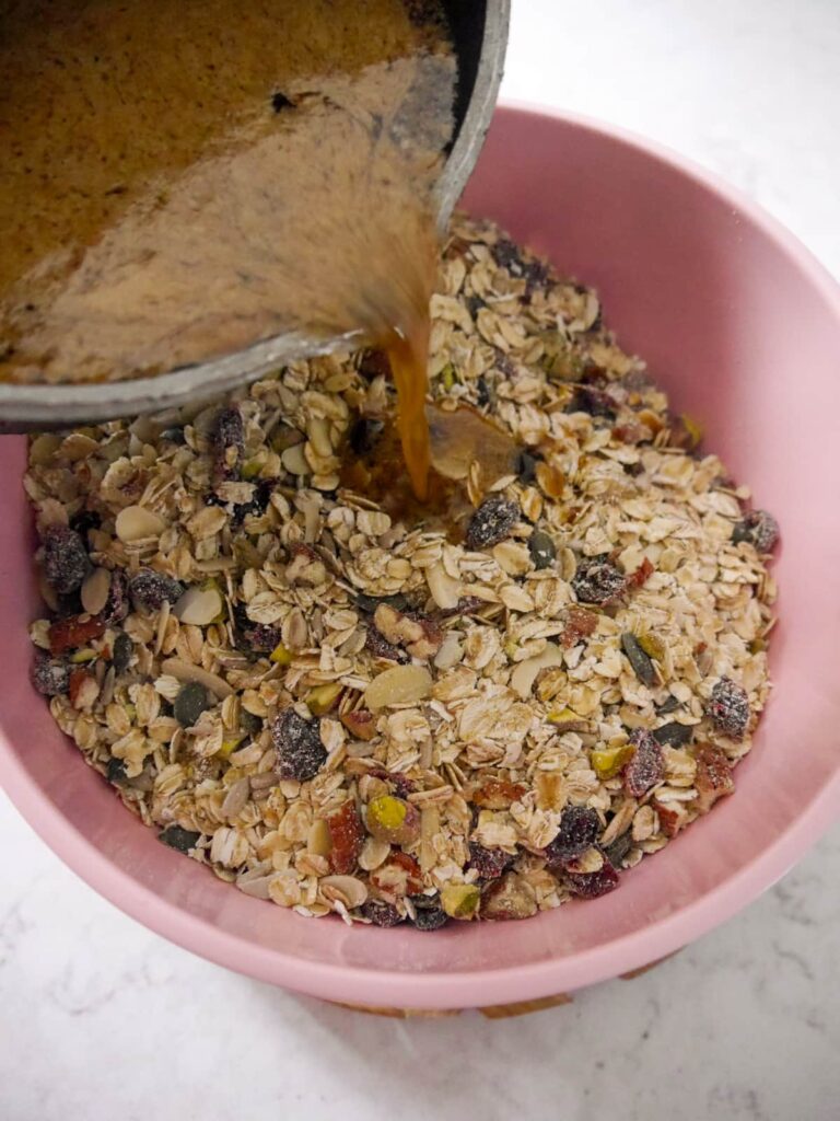 Melted sugar, butter and spices being poured into a bowl of dry flapjack ingredients.