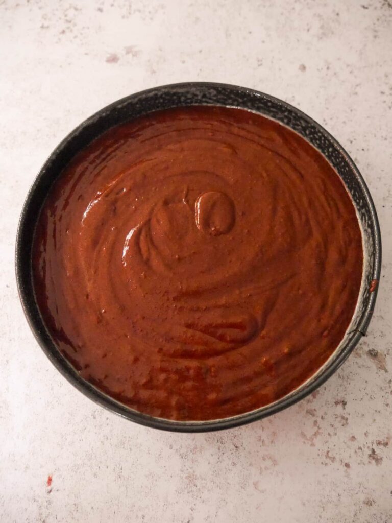 A round baking tin filled with flourless chocolate cake batter.