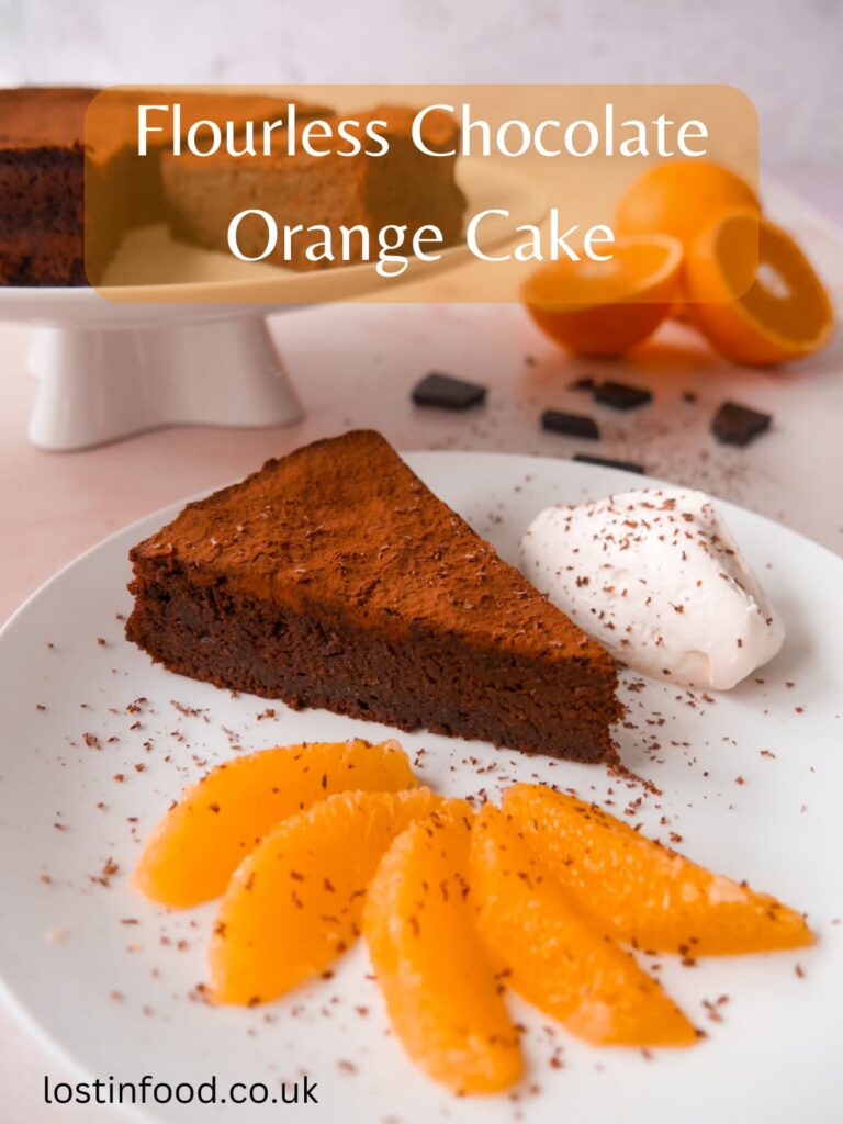 Pinnable image with recipe title and white plate with a sliced flourless chocolate orange cake with a serving of cake with orange slices and whipped cream set alongside.