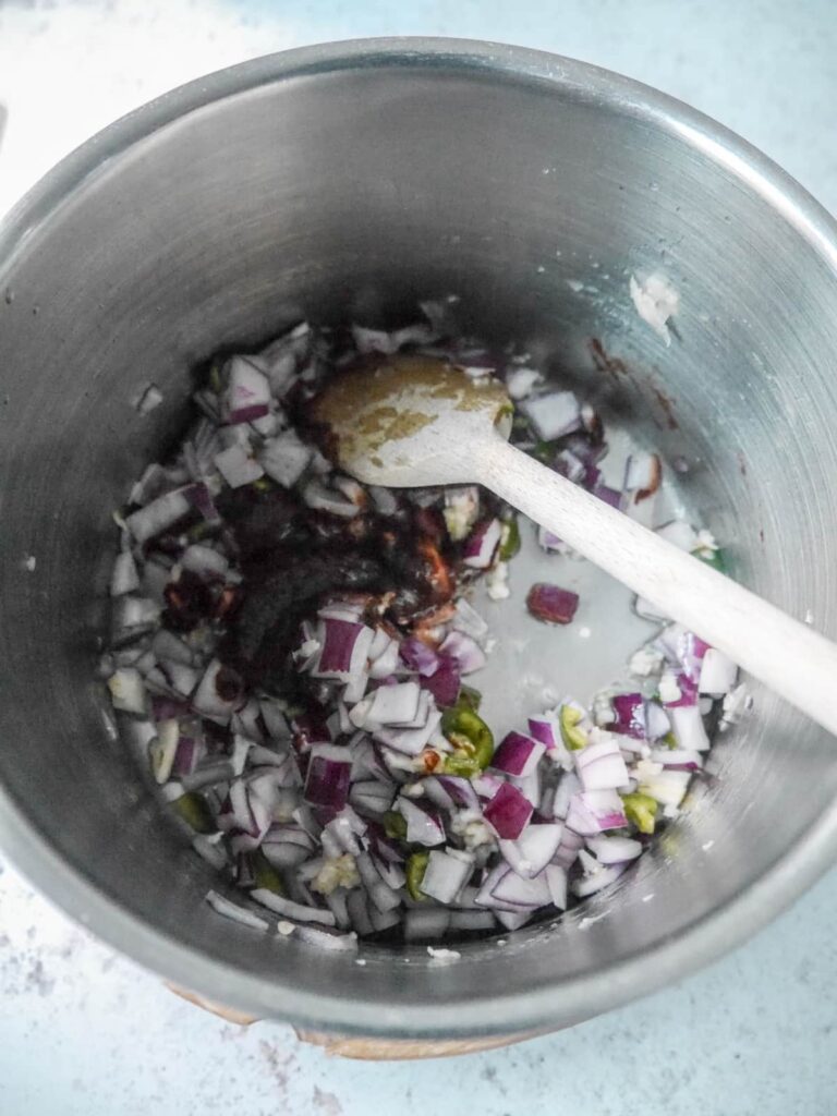 Saucepan with oil, chopped red onion, shopped chilli and chipotle chilli paste.